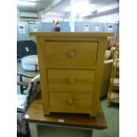 A modern pine three drawer bedside chest