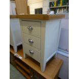 An ivory painted three drawer bedside ch
