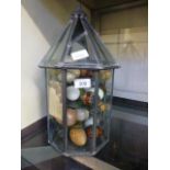 A leaded glass terrarium with a selection of onyx and wooden eggs