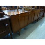A mid 20th century walnut sideboard with two drawers over four cupboard doors on tapering legs