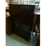 A modern oak cabinet with leaded glazed doors over fall front drawer