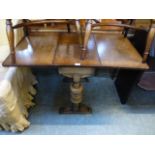 An early 20th century oak drop leaf dining table on turned end supports