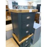 An oak topped and dark grey based three drawer bedside cabinet (16.