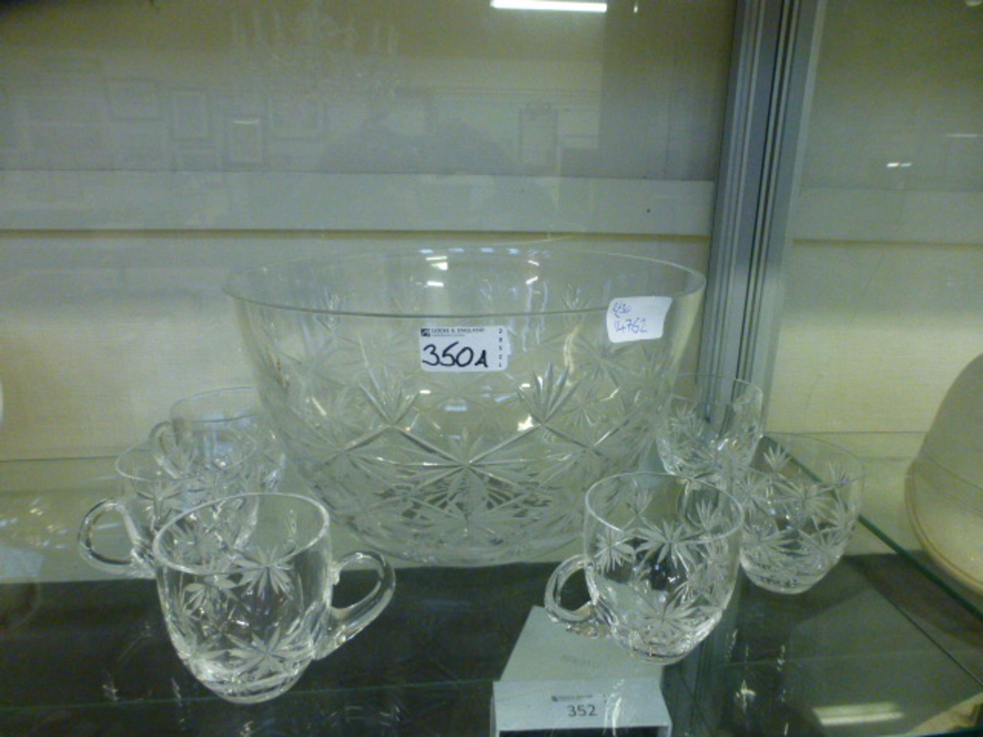 A cut glass punch bowl with matching mugs