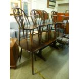 An Ercol table with extension and four (2 plus 2) chairs with fleur de lis design to back