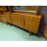 A mid 20th century teak sideboard having four drawers flanked by cupboard doors