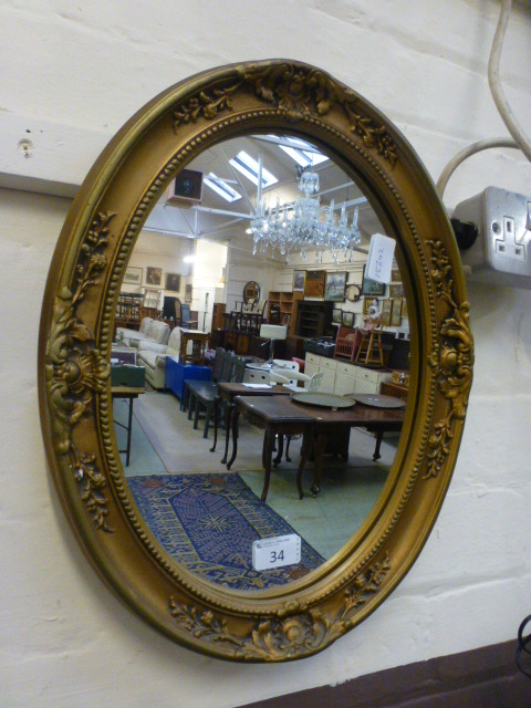 An ornate gilt framed oval mirror