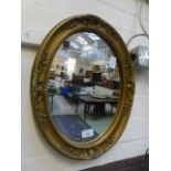 An ornate gilt framed oval mirror