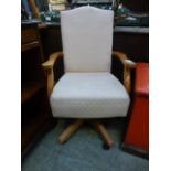 A modern pine framed swivel office chair upholstered in a cut cream fabric