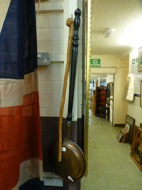 A brass bed warming pan along with a walking stick