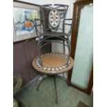 A tiled top metal circular garden table with a pair of similar matching chairs