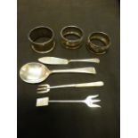 Three silver hallmarked napkin rings together with a silver hallmarked pickle fork,
