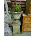 A weathered garden stoneware planter on plinth
