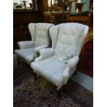 A pair of early 20th century wing back armchairs upholstered in a patterned white gold fabric on