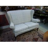 An early 20th century high back wing two seater sofa with cabriole supports