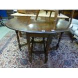 An early 20th century oak oval topped drop leaf table