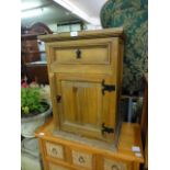 A modern pine bedside cupboard having drawer above door