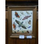 A framed hand painted ceramic tile depicting moths,
