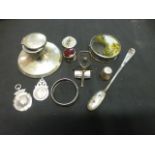 An assortment of silver and white metal items to include brooch, fob, inkwell, spoon etc.