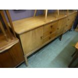 A mid 20th century walnut sideboard, two cupboard doors flanking three drawers,