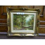 A gilt framed oil of river flowing through wooded scene