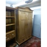 A waxed pine two door wardrobe having two drawers to base