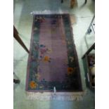 A small rectangular purple and green floral decorated ground rug