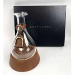 RALPH LAUREN STIRRUP DECANTER, glass with leather and brass collar on leather base, 33cm H.
