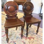 HALL CHAIRS, a pair, Victorian mahogany with carved roundel backs on turned front supports,