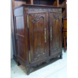 CUPBOARD, early 19th century French carved oak with a pair of panelled doors,