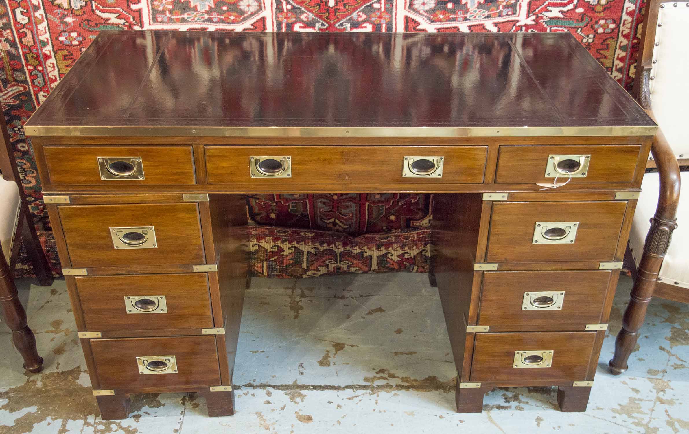 CAMPAIGN STYLE DESK, mahogany and brass bound with leather top above nine drawers,