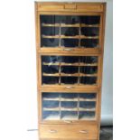 HABERDASHERY CABINET, early 20th century English oak, with three glazed rising doors,