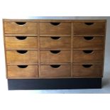 BANK OF DRAWERS, mid 20th century beech with twelve shaped top drawers and plinth base,