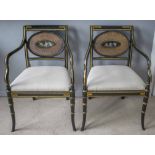 REGENCY DESIGN OPEN ARMCHAIRS, a pair, ebonised with gilt detail, caned back and painted cherubs,