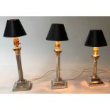 LAMPS, a set of three silver plated Corinthian capped, varying heights with shades,