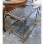 TROLLEY, brass and smoked glass on large wheels, 47cm x 76cm H x 73cm.