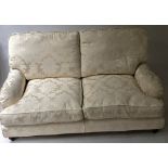 HOWARD STYLE SOFA, with two seat and back cushions in cream silk on turned supports to castors,