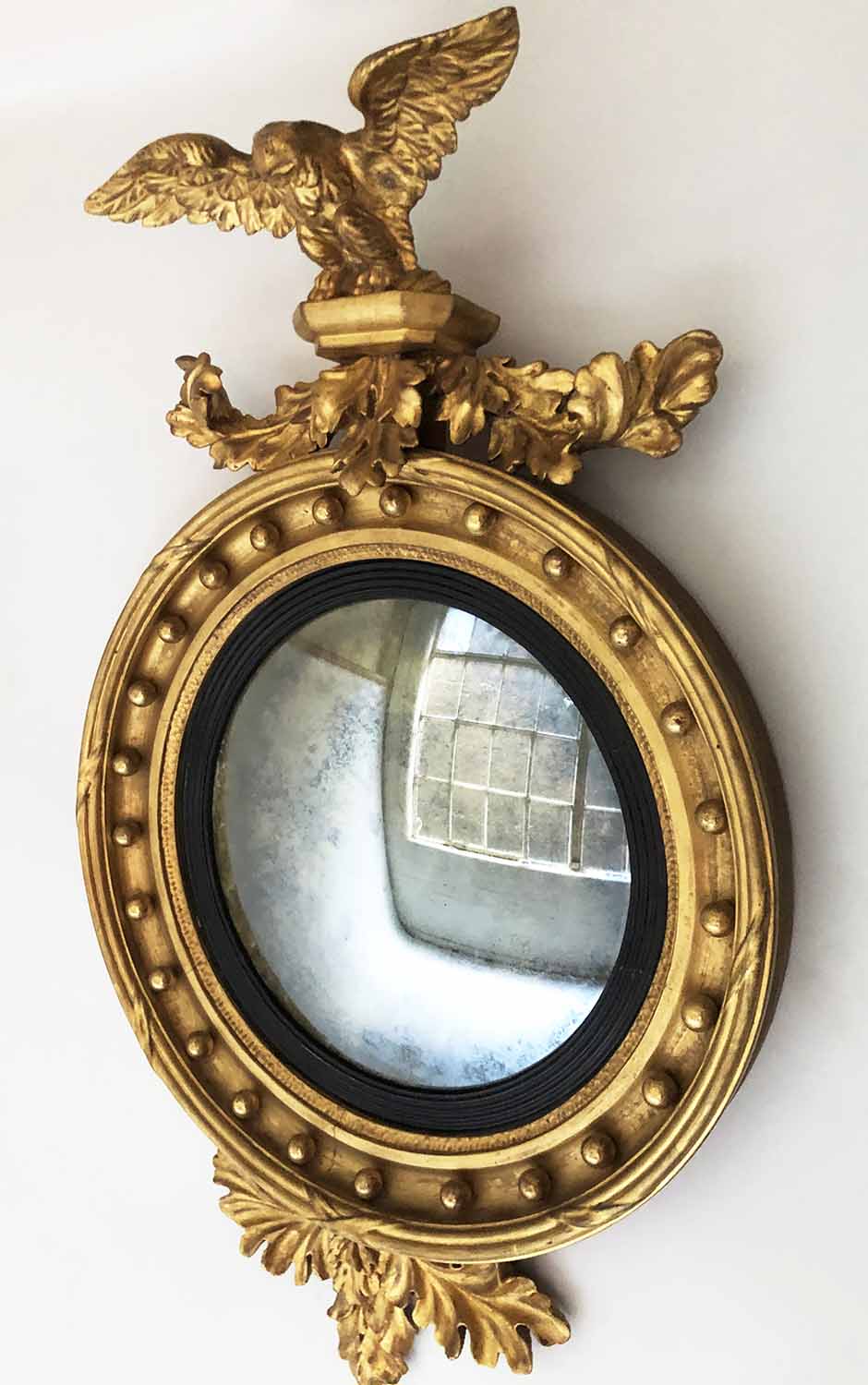 REGENCY CONVEX WALL MIRROR, carved giltwood the circular plate with ebonised slip,