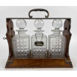 BETJEMANN'S PATENT TANTALUS, Victorian oak and silver plate, with three cut glass decanters,