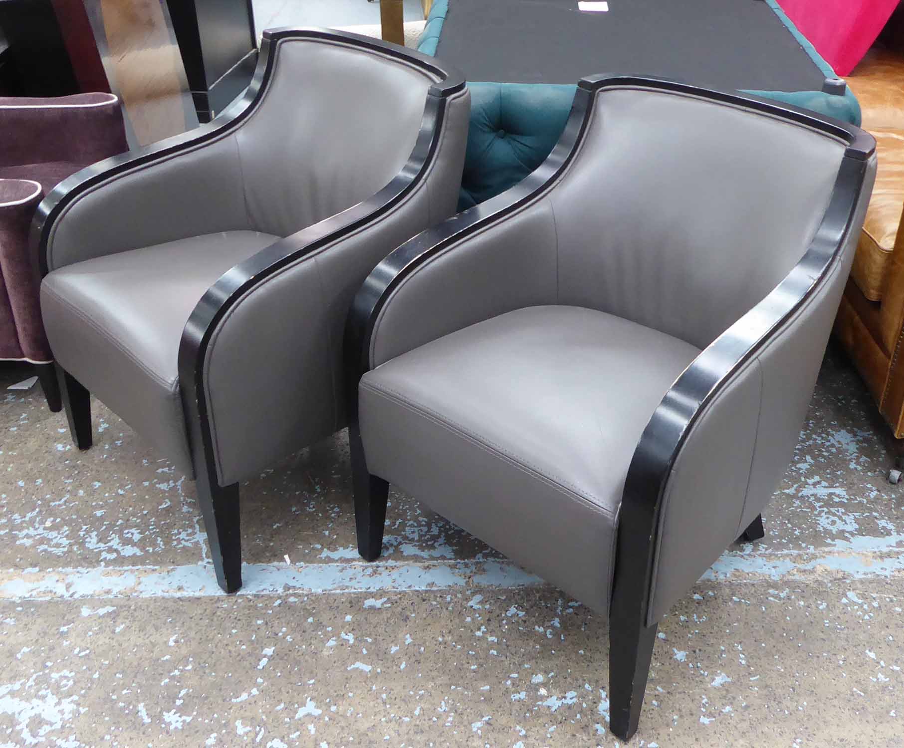 CONTEMPORARY ARMCHAIRS, grey leather with ebonised showframes, each 65cm W x 83cm H.