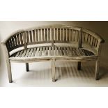 'BANANA' GARDEN BENCH, silvered weathered teak, of slatted construction and bowed outline, 160cm W.