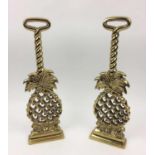 DOOR STOPS, a pair, cast brass modelled as pineapples, 40cm H. (2)