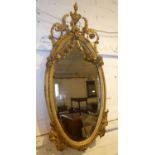 WALL MIRROR, late 19th century French oval giltwood and gesso with an urn finial and scroll, leaf