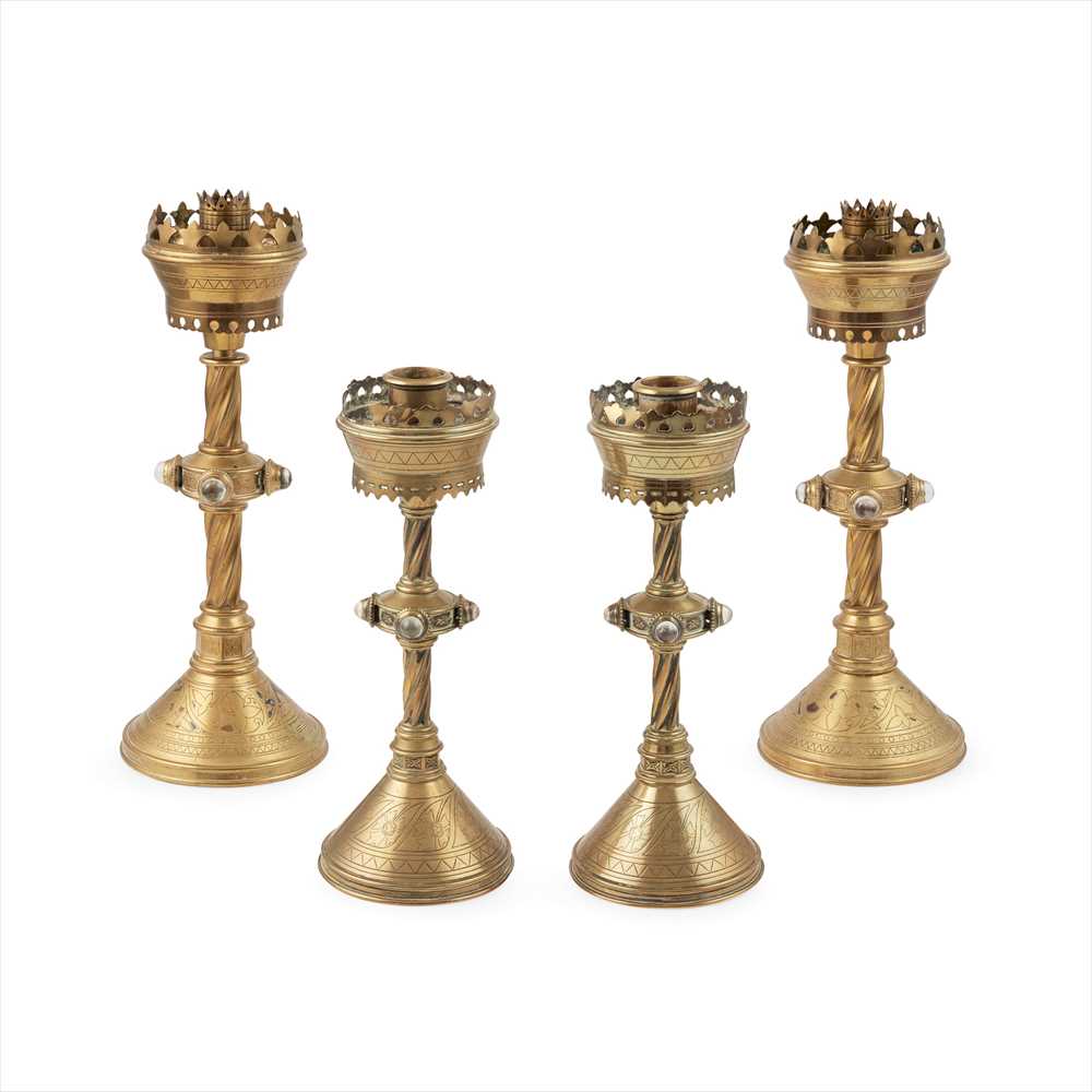 ENGLISH SCHOOL GROUP OF FOUR OF GOTHIC REVIVAL BRASS AND JEWELLED CANDLESTICKS, CIRCA 1880