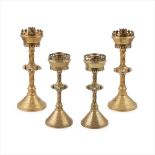 ENGLISH SCHOOL GROUP OF FOUR OF GOTHIC REVIVAL BRASS AND JEWELLED CANDLESTICKS, CIRCA 1880