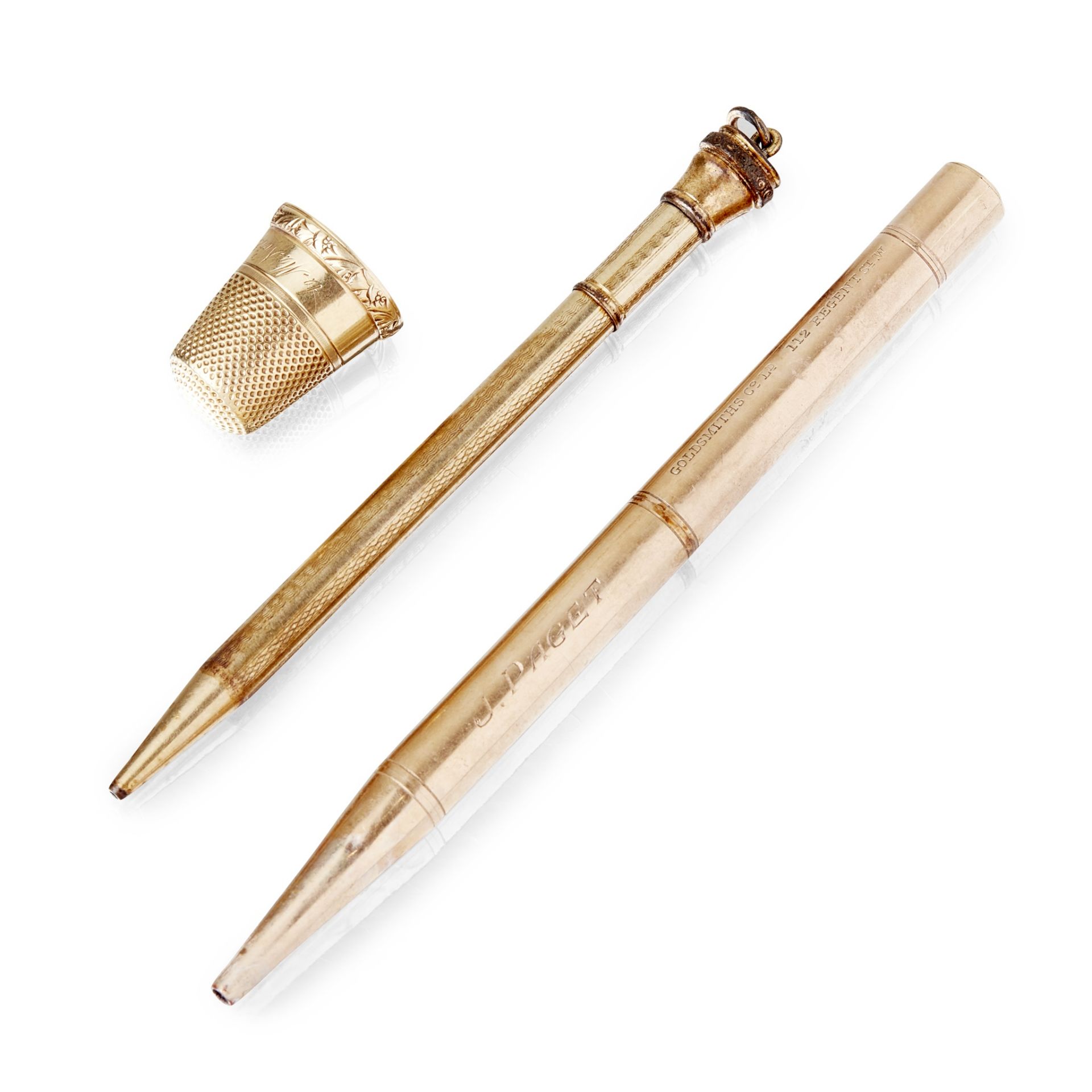 A yellow metal thimble and a propelling pencil and a pen