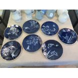 Seven Pate sur Pate style decorative plates, depicting swallows flying among foliage, on a cobalt