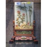 A Chinese green hardstone pietra dura panel, depicting bamboo and sunflowers, in a carved hardwood