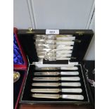 A cased set of fruit knives and forks with blades in silver and handles in mother of pearl