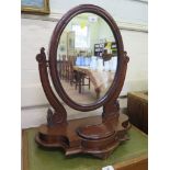 A Victorian mahogany toilet mirror, the oval plate within scroll supports and shaped base with